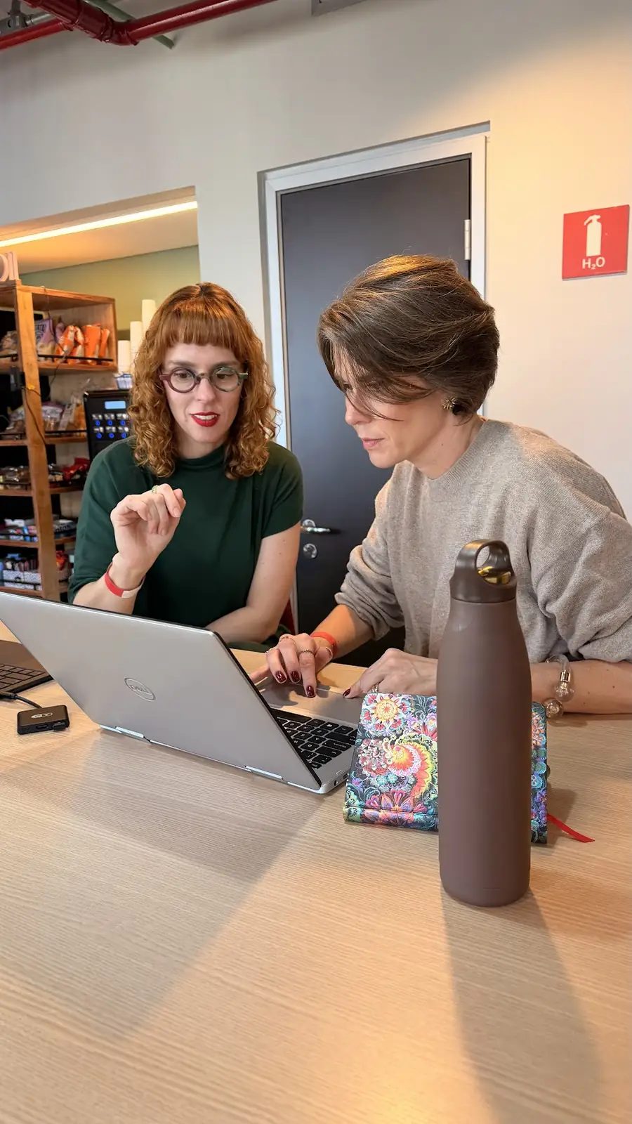 Mari acompanhando uma participante durante uma prática no computador
